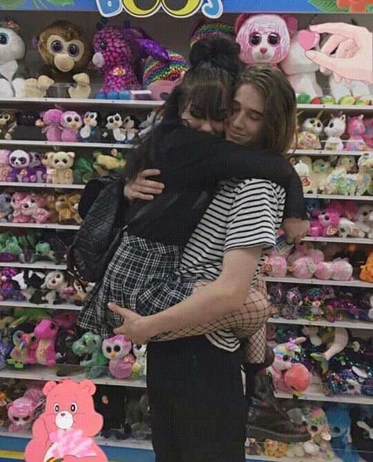 two girls hugging each other in front of stuffed animals and teddy bears on the shelves