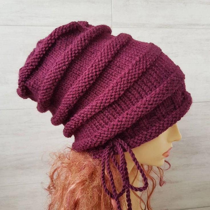 a mannequin head wearing a purple knitted hat with braids on it