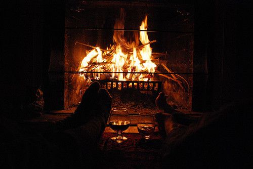 two people sitting in front of a fire place with their feet on the coffee table