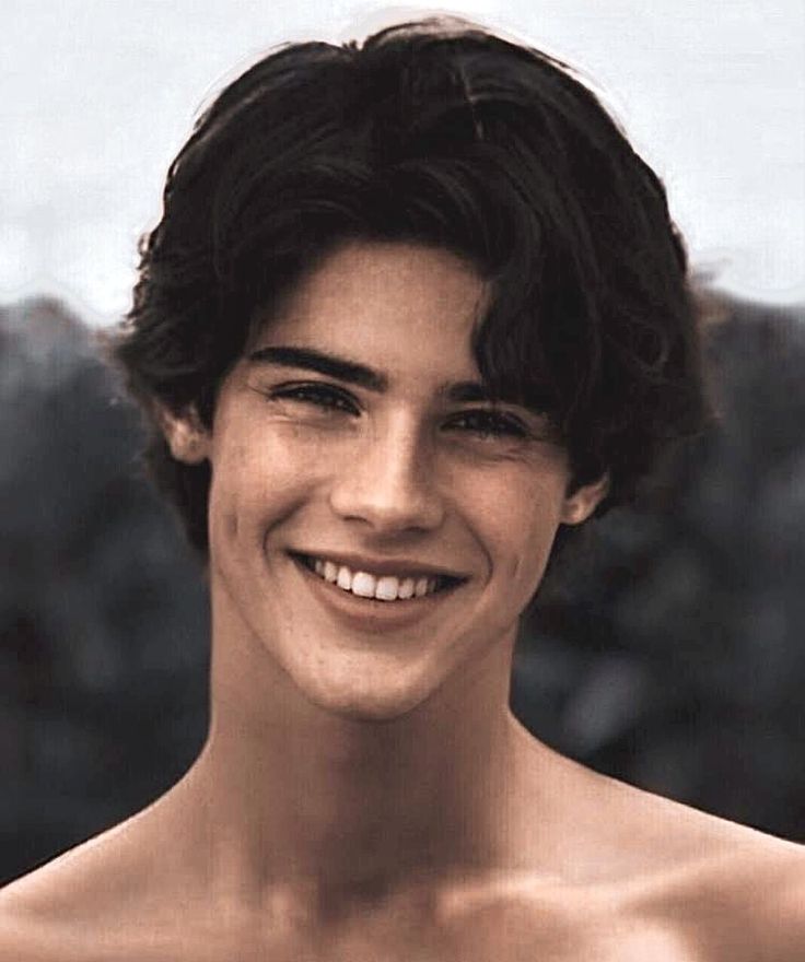 a young man with no shirt smiling at the camera