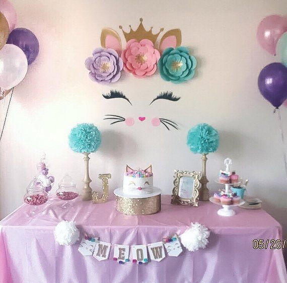 a table topped with cake and balloons in front of a wall mounted unicorn head on the wall