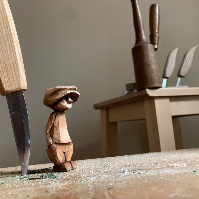 a small wooden toy standing next to a knife