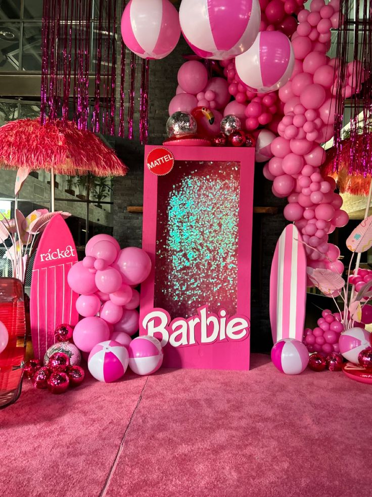 pink and white balloons are hanging from the ceiling above a table with an advertisement on it