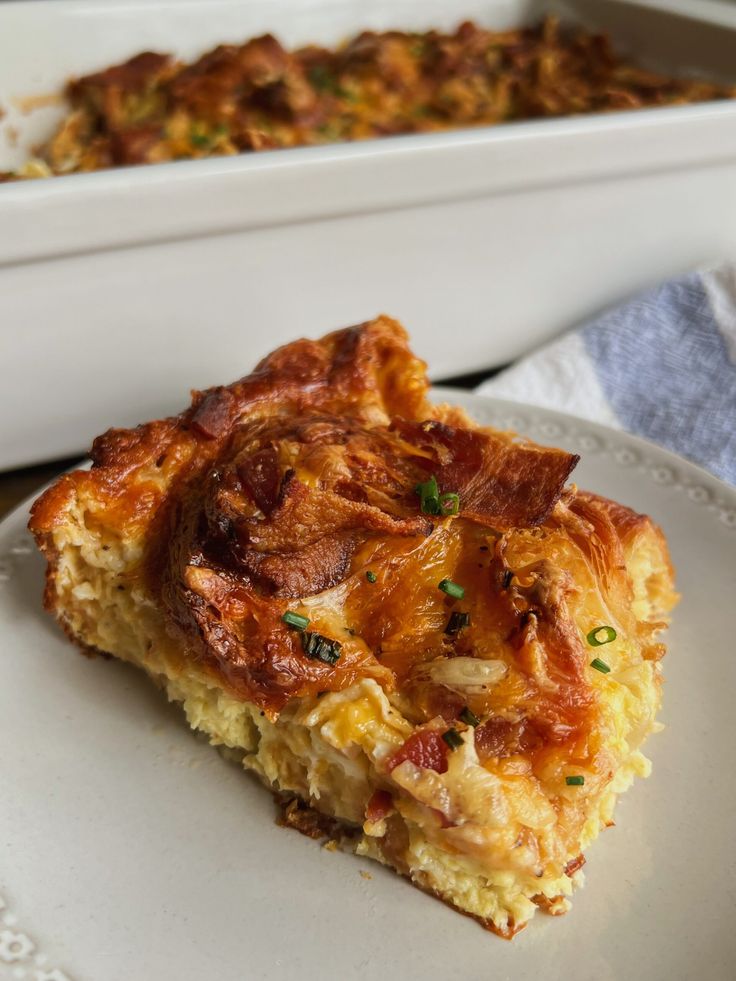 a piece of quiche on a white plate next to a casserole dish