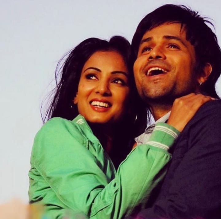 a man and woman hugging each other in front of a blue sky with the sun shining on them