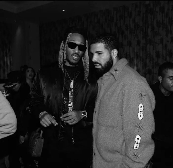 two men standing next to each other in front of a group of people wearing sunglasses