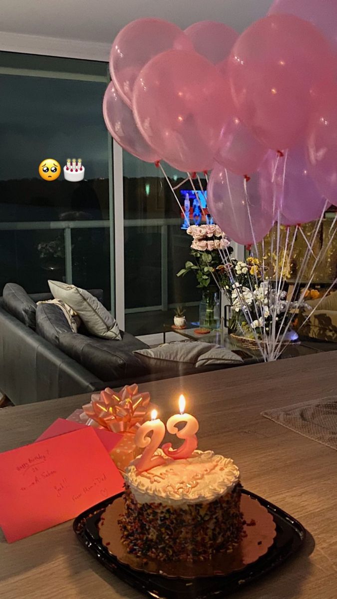 a birthday cake sitting on top of a black plate with balloons in the shape of numbers