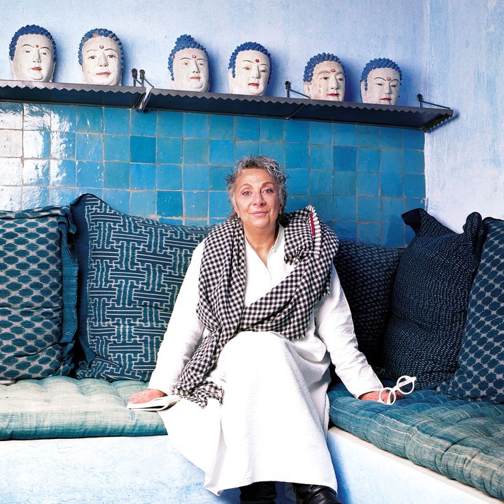 a woman sitting on top of a couch in front of a wall with many head heads