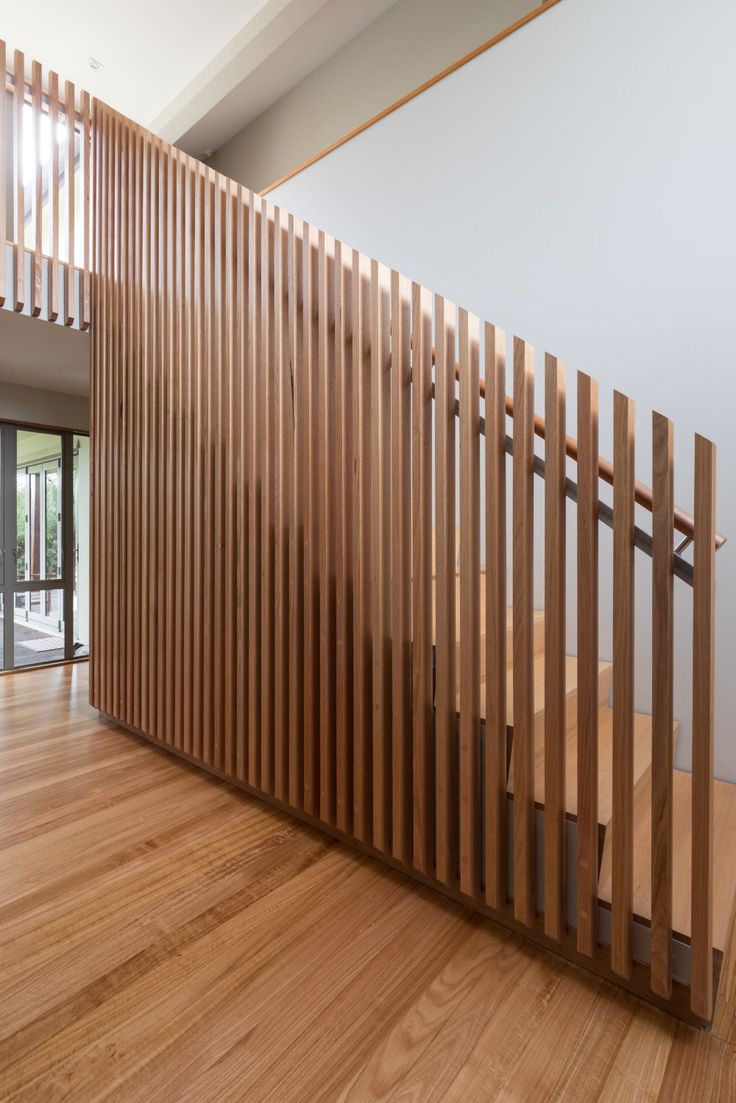 an empty room with wood slats on the wall and wooden flooring in front of it