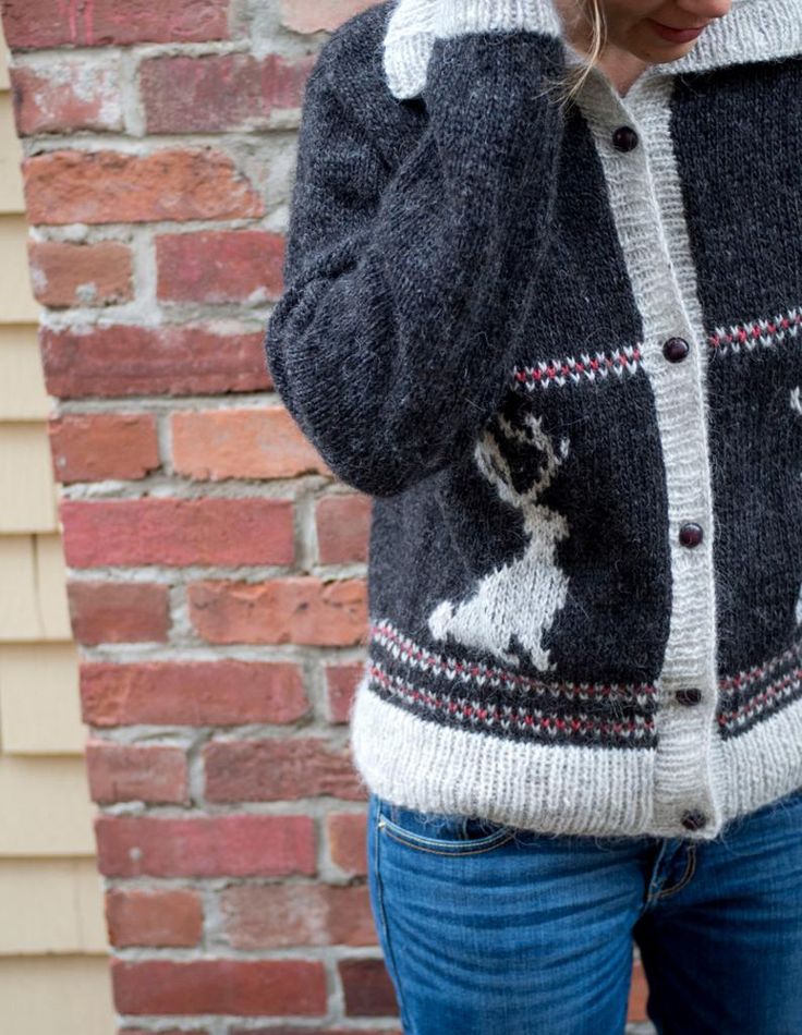 a woman standing in front of a brick wall talking on a cell phone while wearing a sweater