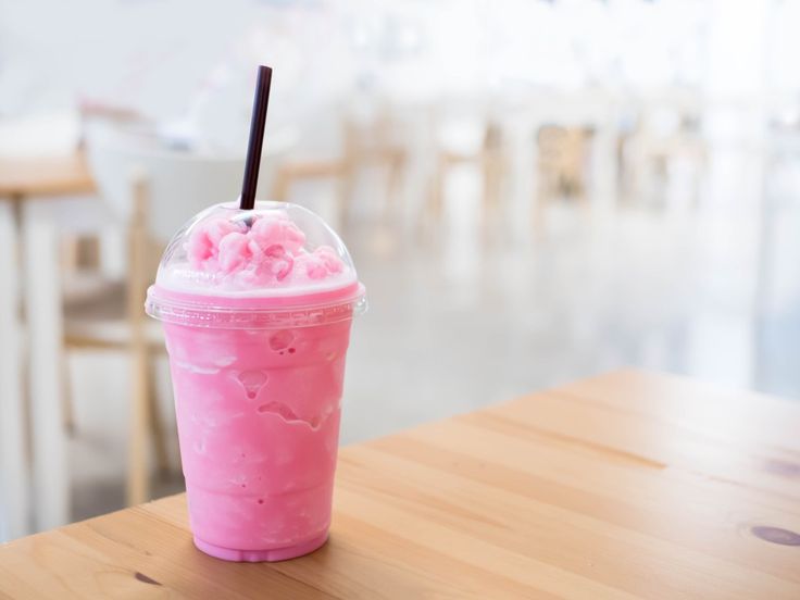 a pink drink sitting on top of a wooden table