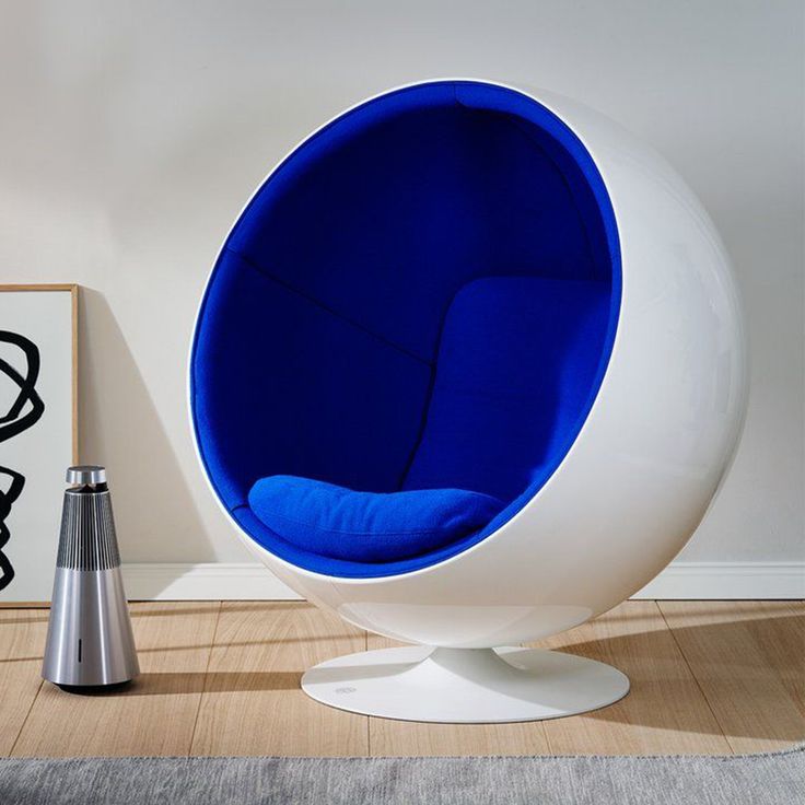 a white and blue chair sitting on top of a wooden floor next to a vase