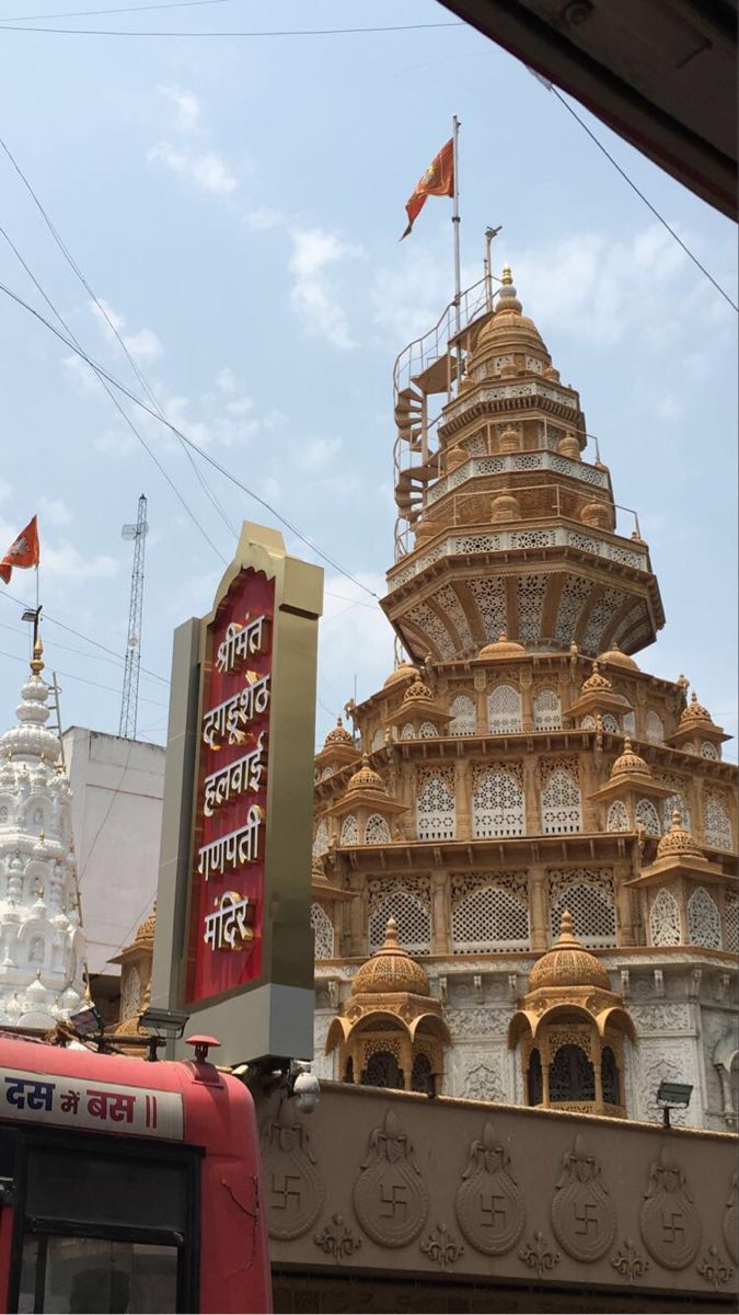 an ornate building with flags flying in the wind and a bus parked outside on the street