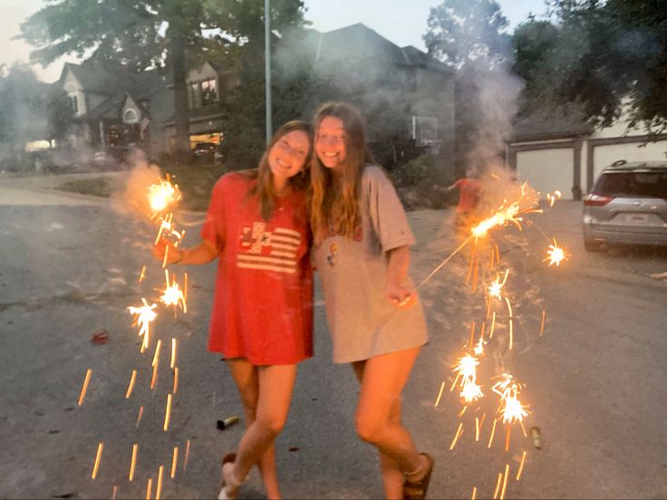 two girls are posing with sparklers in the street