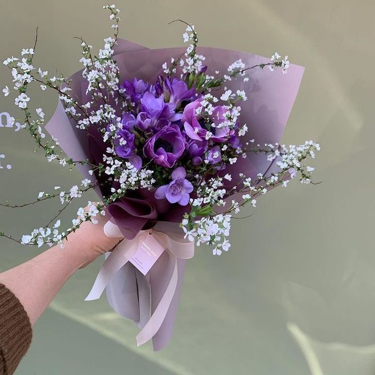 a person holding a bouquet of purple flowers