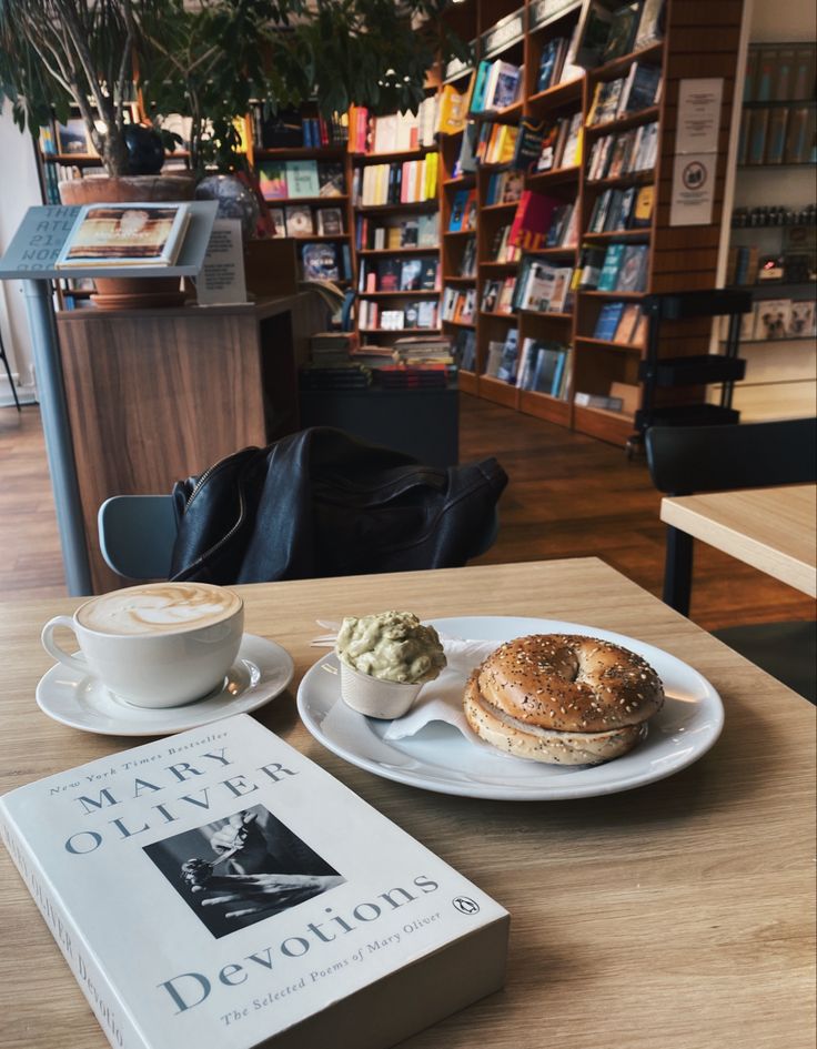 there is a bagel and coffee on the table in front of bookshelves