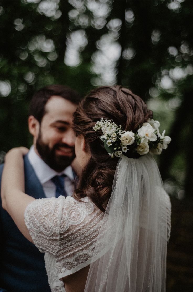 a bride and groom embracing each other in the woods