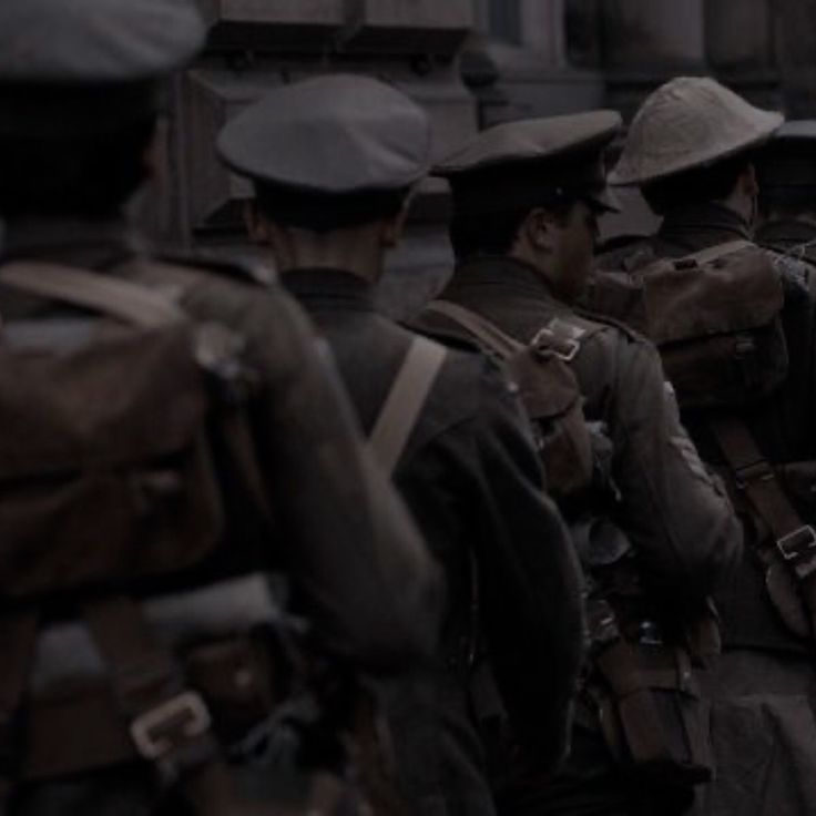 a group of men in uniforms standing next to each other on the street with buildings in the background