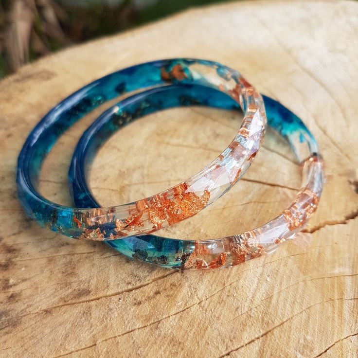 two bracelets sitting on top of a piece of wood