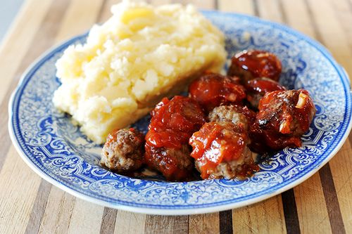 meatballs, mashed potatoes and gravy are on a blue and white plate