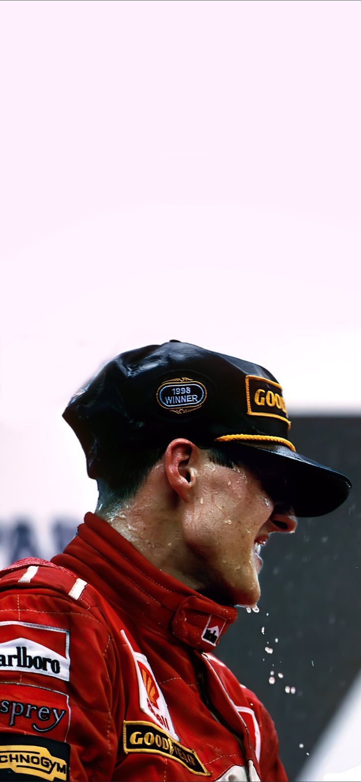 a man in a red racing suit and black hat with water splashing on his face