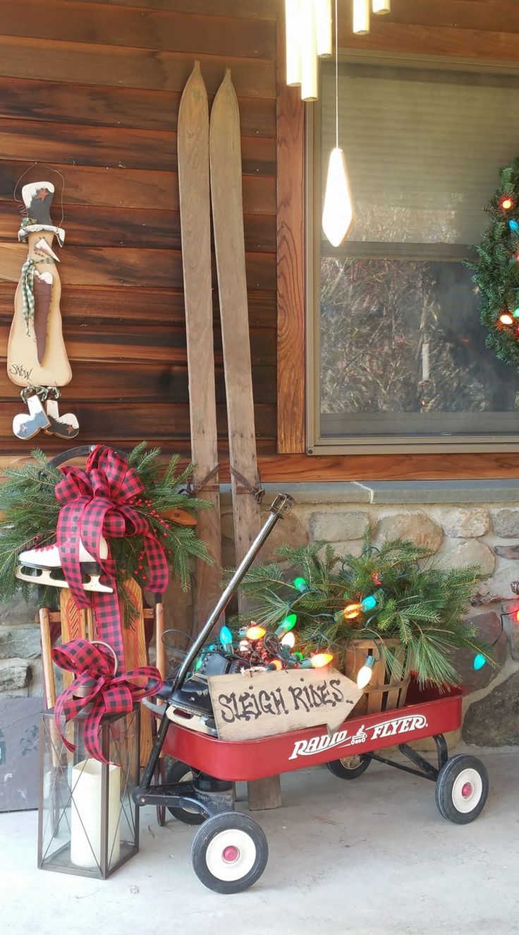 a red wagon with christmas decorations and skis on the side of a cabin door