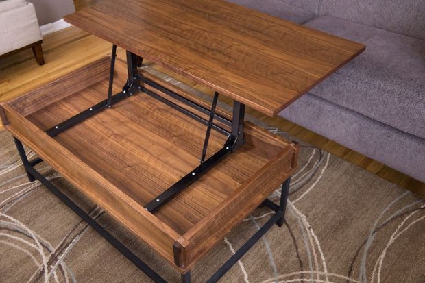 a wooden table sitting on top of a rug next to a gray couch in a living room