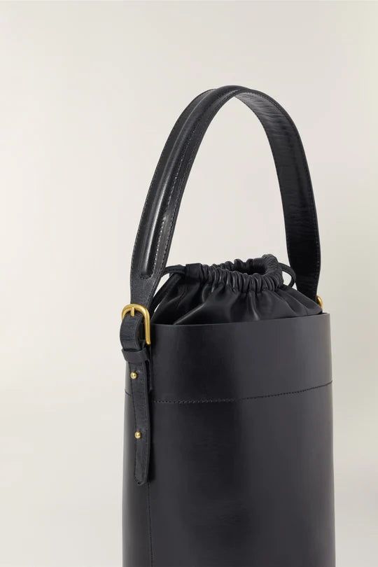 Black leather bucket bag- Hand, shoulder, or cross-body bag- Golden metallics- Fastens with an inner leather drawstring pouch- Height 26 cm, depth 18 cm- One removable leather handle - length 77 cm - One removable cotton handle - length 106 cm Everyday Bucket Bag With Adjustable Strap And Round Handle, Luxury Bucket Bag With Leather Handles For Shopping, Modern Bucket Bag With Detachable Strap And Round Handle, Modern Bucket Bag With Round Detachable Handle, Luxury Shopping Bucket Bag With Leather Handles, Luxury Bucket-shaped Hobo Bag With Handle Drop, Chic Bucket Bag With Adjustable Strap And Round Handle, Evening Bucket Hobo Bag With Detachable Handle, Formal Crossbody Bucket Bag With Leather Handles