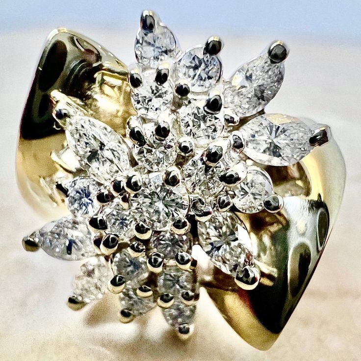 Fine vintage diamond cluster cocktail ring crafted in 14 karat yellow and white gold. It is set with 14 round diamonds weighing approximately 0.40 CTTW, and 6 Marquise diamonds weighing approximately 0.60 CTTW. Total carat weight is 1 CTTW. The stones are approximately G-H color, VS2-SI1 clarity. Stamped 14K. Weighs 6.9 grams. Size 7 US / N 1/2 - O UK. > Resizing included. This ring can be resized to fit most fingers. Please contact us for details. Resized rings are final sale. Free resizing doe Yellow Gold Cluster Ring With Cubic Zirconia, Yellow Gold Diamond Cluster Ring, Yellow Gold Diamond Ring With Cluster Accents, Fine Jewelry Yellow Gold Cluster Diamond Ring, Diamond Cluster Ring In Fine Jewelry Style, 14k Gold Cluster Diamond Ring In Diamond White, Diamond White Cluster Diamond Ring, Yellow Gold Cluster Diamond Ring With Prong Setting, Yellow Gold Diamond Ring With Brilliant Cut Cluster