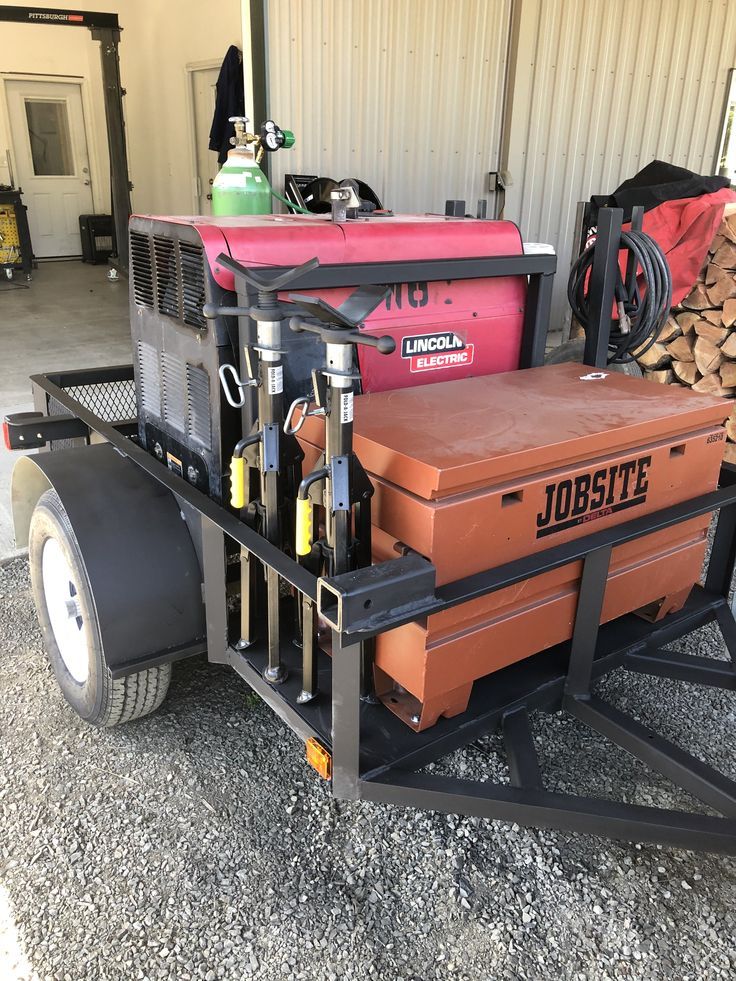 a red and black cart filled with equipment next to a garage door in the background