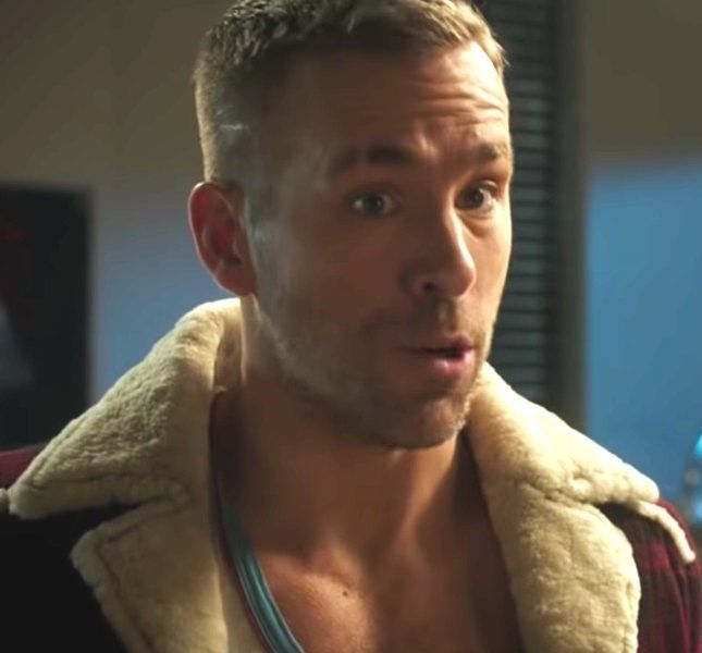 a shirtless man wearing a jacket and looking at the camera with an intense look on his face