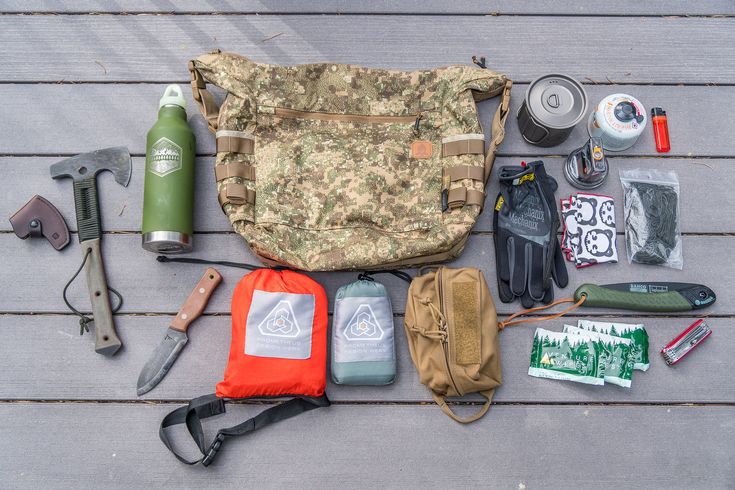 an assortment of items laid out on a wooden table including a backpack, knife and other camping gear