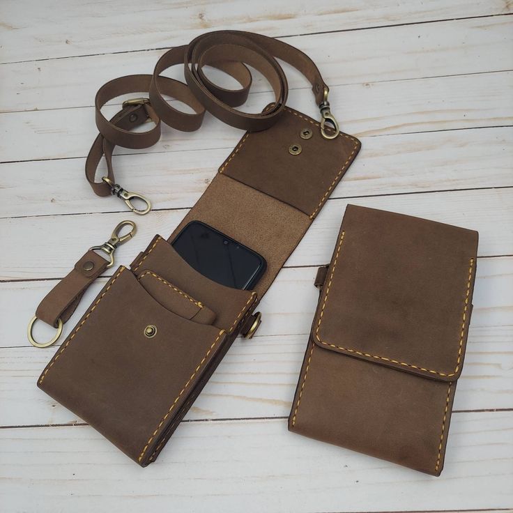 a cell phone in a leather case on a white wooden table with a lanyard