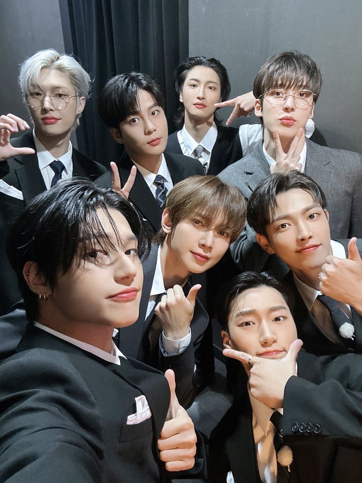 a group of young men in suits posing for a photo with their fingers up and pointing at the camera