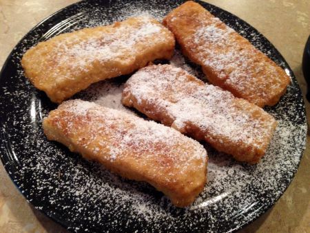 some type of dessert on a black plate with sugar sprinkled around the edges