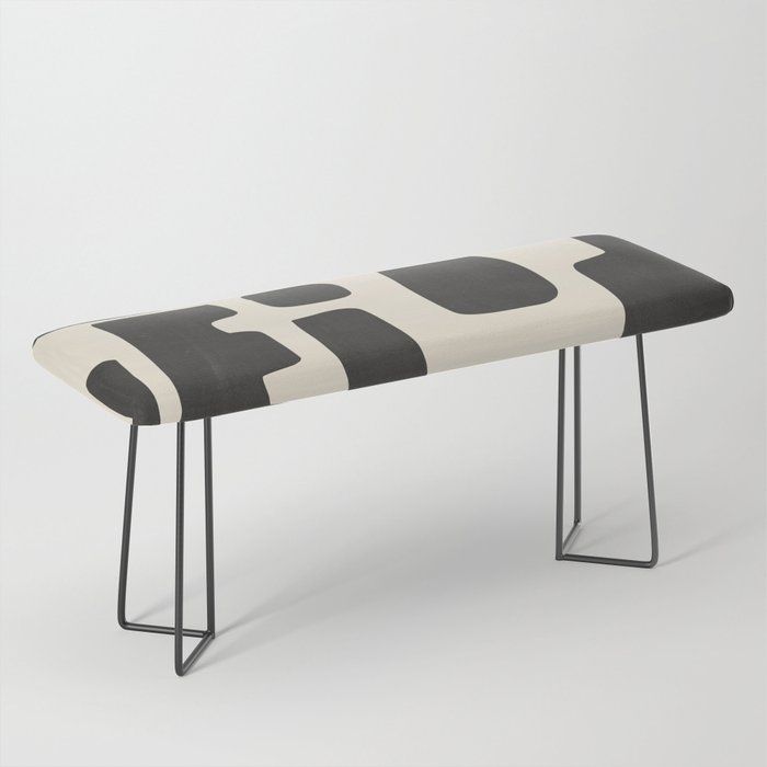 a black and white bench sitting on top of a metal frame legs with an upholstered seat