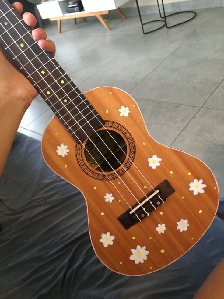 a person holding an ukulele with flowers on it