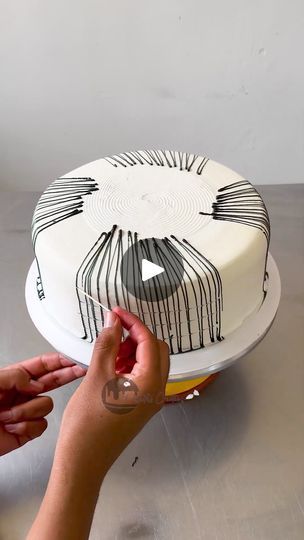 someone is decorating a cake with black and white icing on the bottom layer