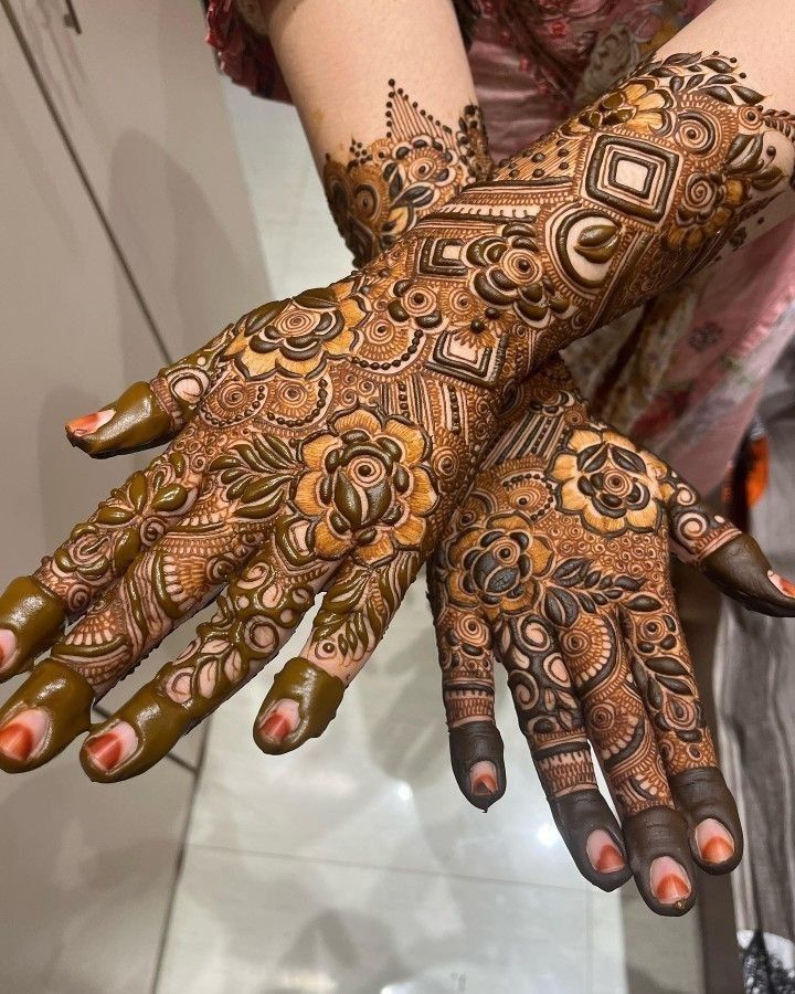 a woman's hands with hennap on her arm and hand, all covered in intricate designs