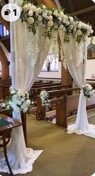 an aisle decorated with white flowers and greenery