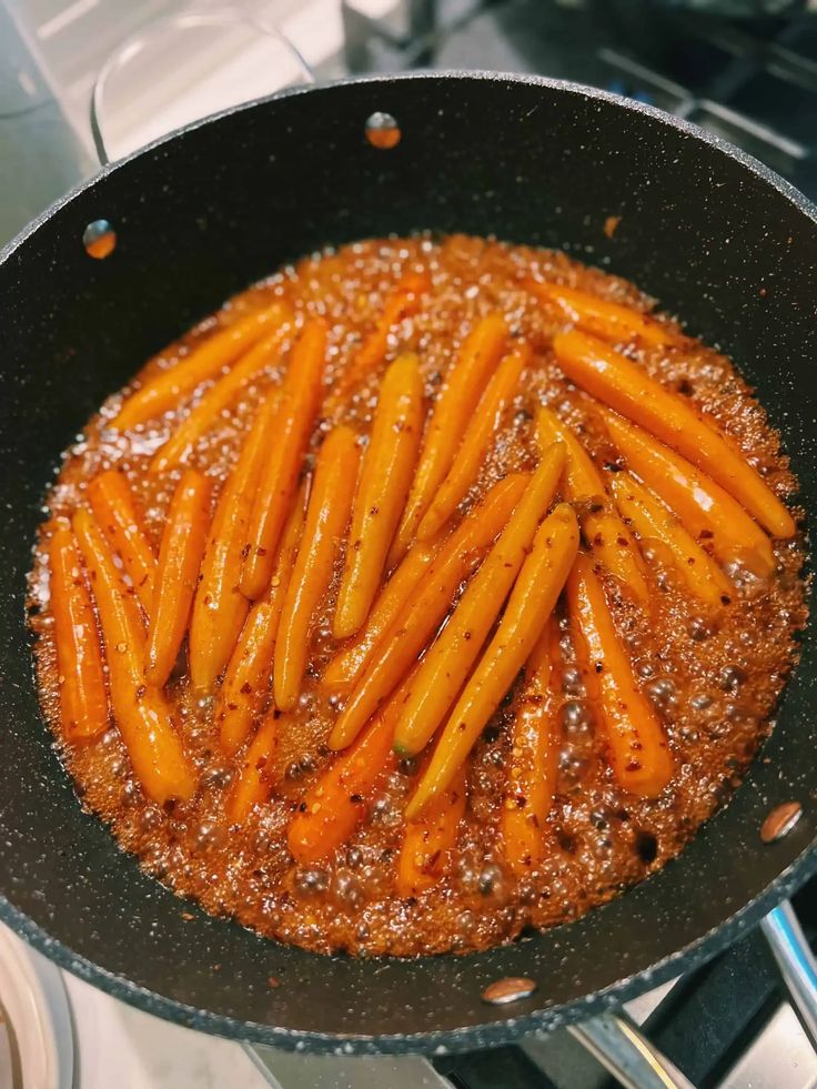 carrots being cooked in a frying pan on the stove