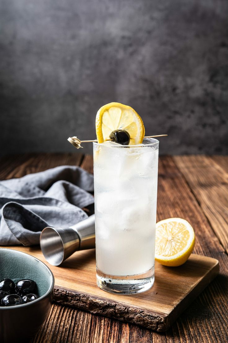 a glass filled with ice and lemon on top of a wooden table