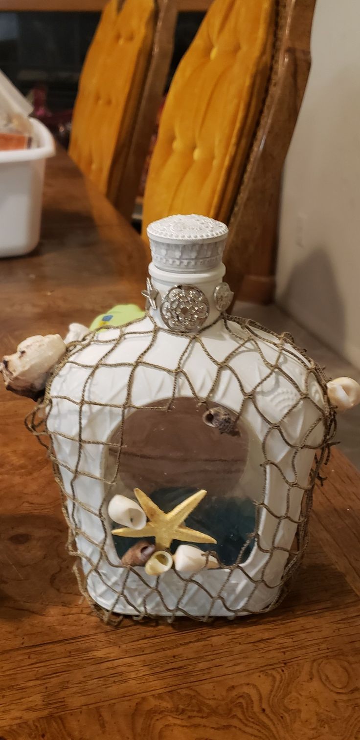 a bottle that is sitting on a table with shells and starfishs in it