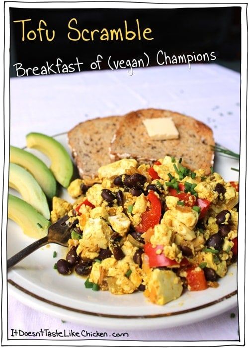 scrambled eggs with black beans and avocado on a plate next to sliced bread