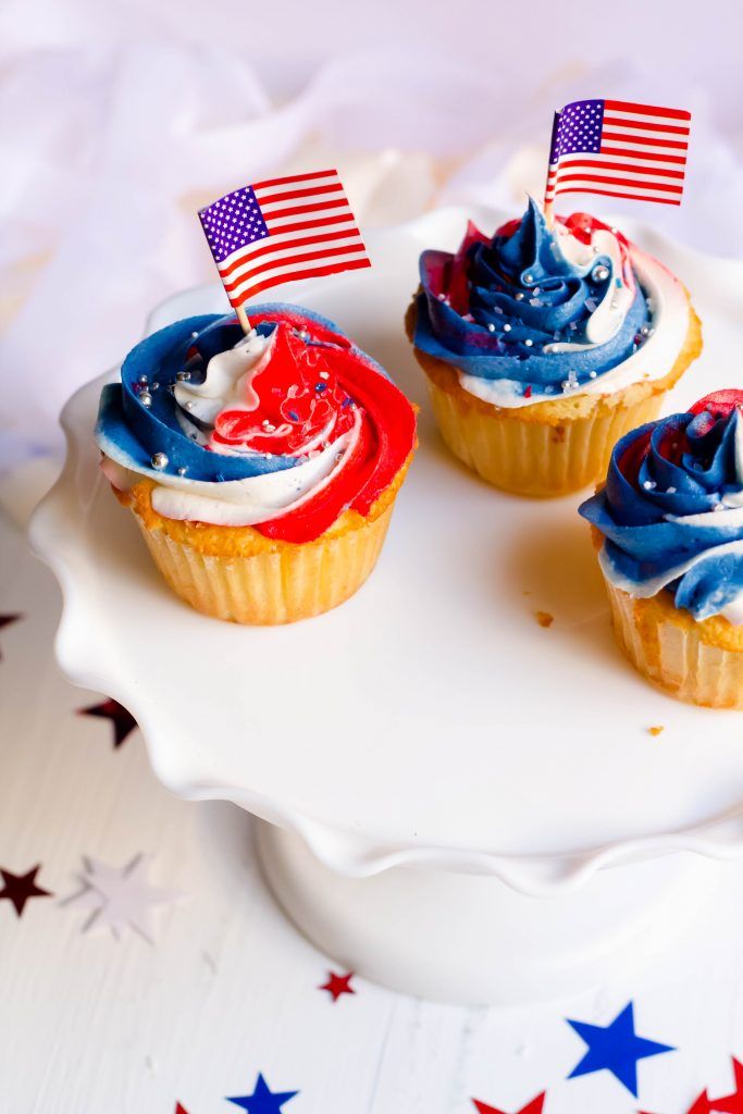 three cupcakes with red, white and blue frosting on a cake plate