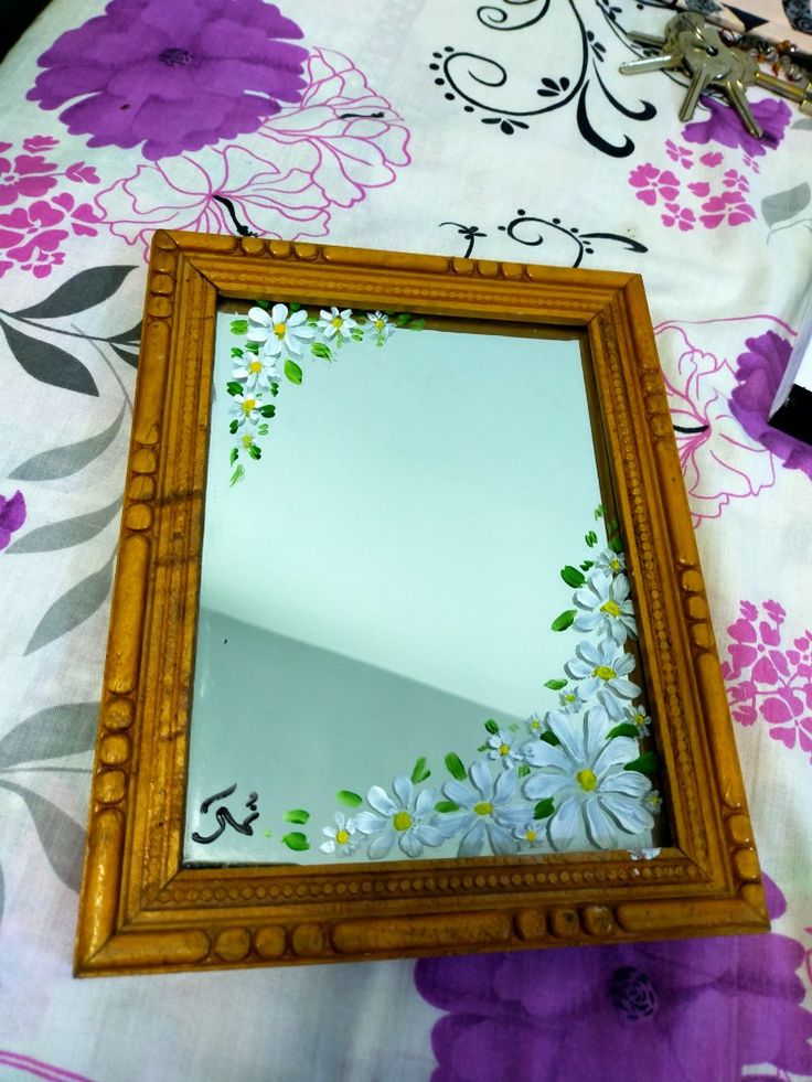 a mirror sitting on top of a table next to a purple flower covered table cloth