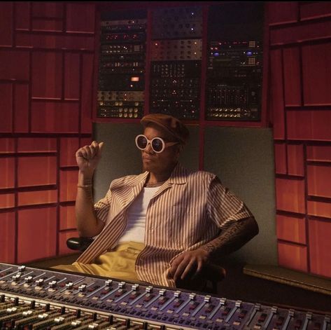 a man wearing sunglasses sitting in front of a mixing desk with sound equipment on it