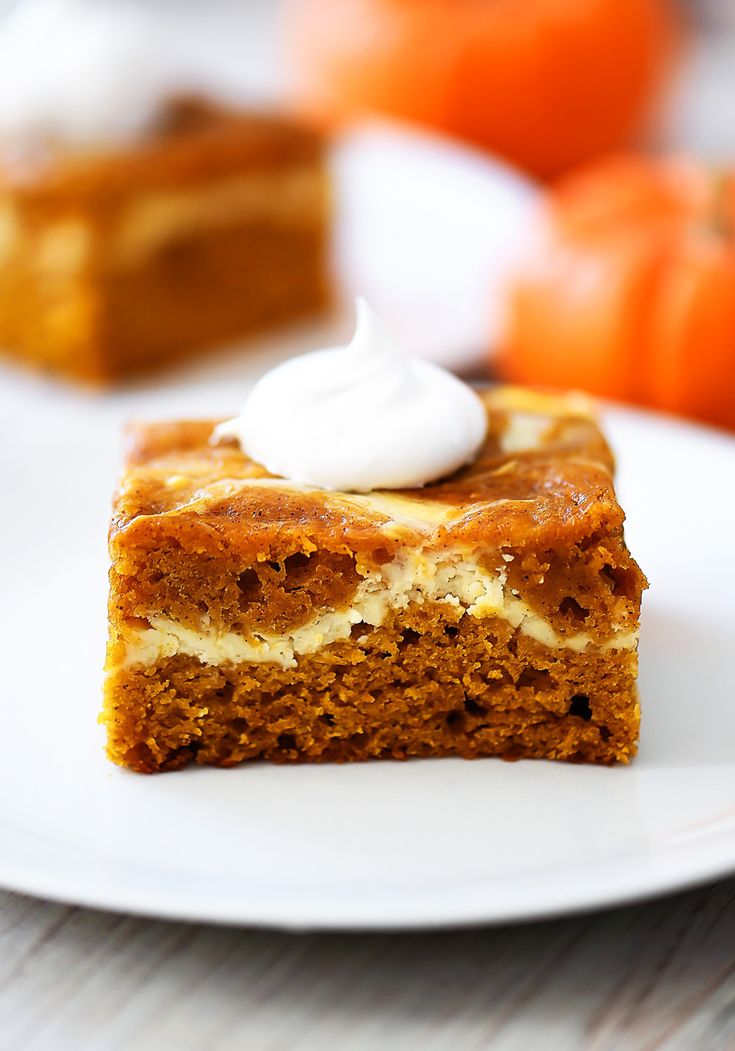 a piece of cake sitting on top of a white plate next to an orange pumpkin