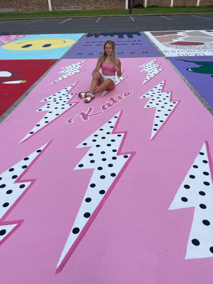 a woman sitting on top of a pink carpet covered in dots and lightning signs,