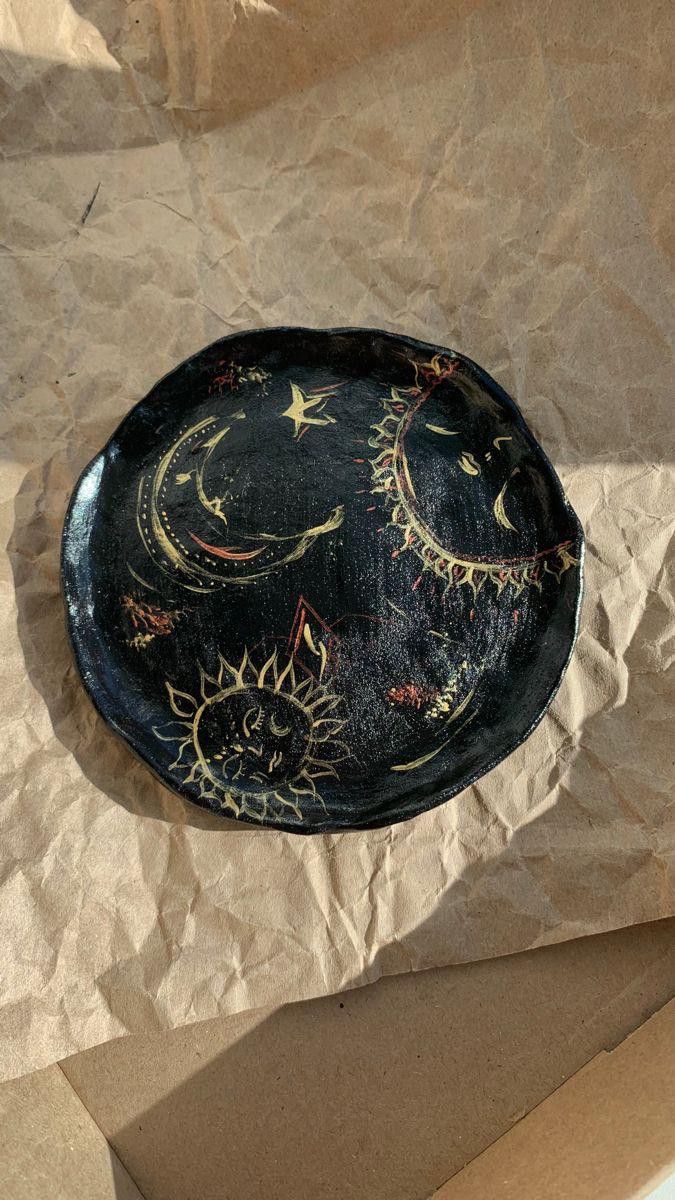 a decorative black plate sitting on top of a piece of brown paper with sun and moon designs